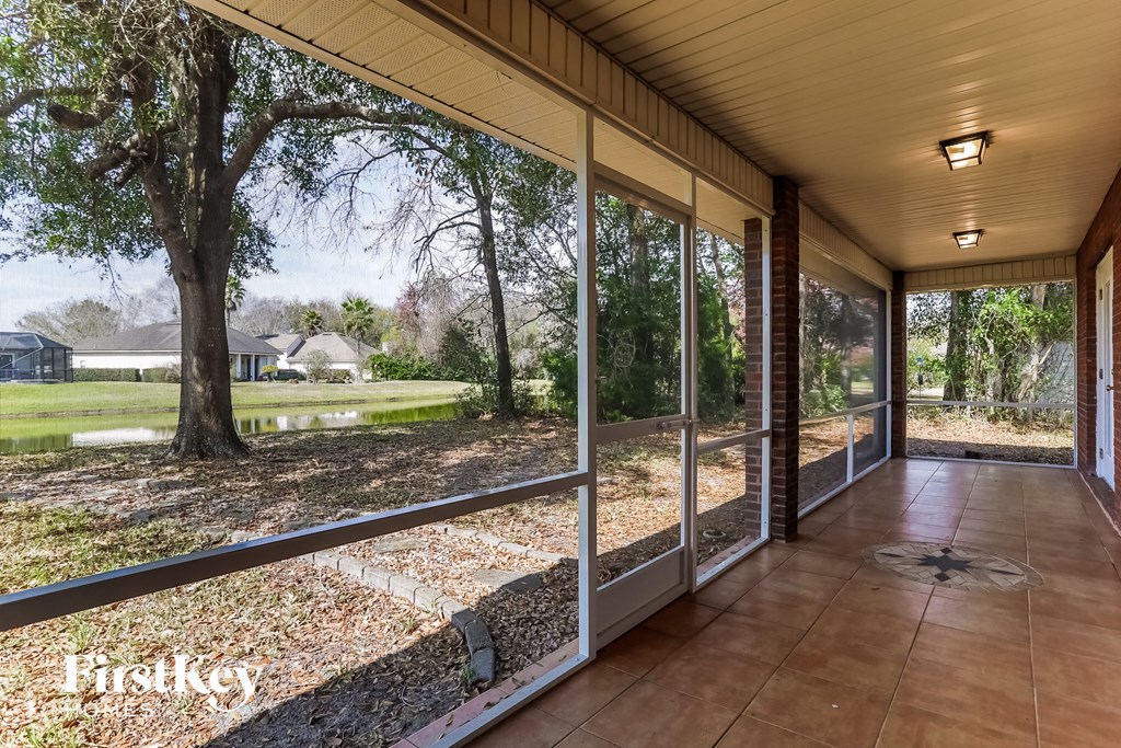 a porch with a view of the yard and a tree