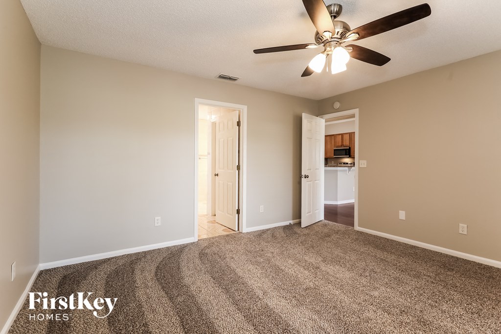a spacious living room with carpet and a ceiling fan