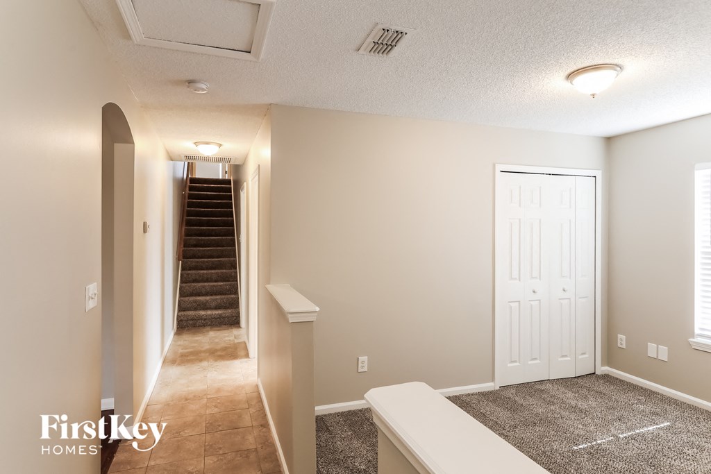 the living room and hallway of an empty house with a staircase