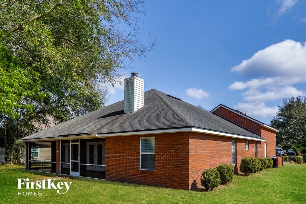 a red brick house with a green lawn and a tree