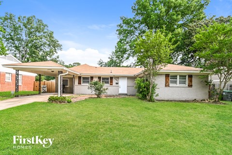 A house with a lawn and trees in front of it.
