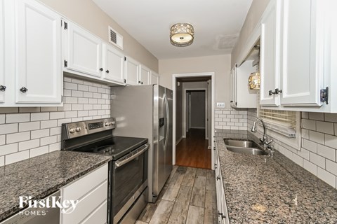 A kitchen with white cabinets and a granite countertop.