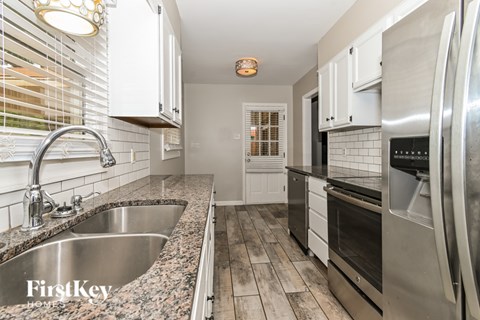 A kitchen with a stainless steel refrigerator and a granite countertop.