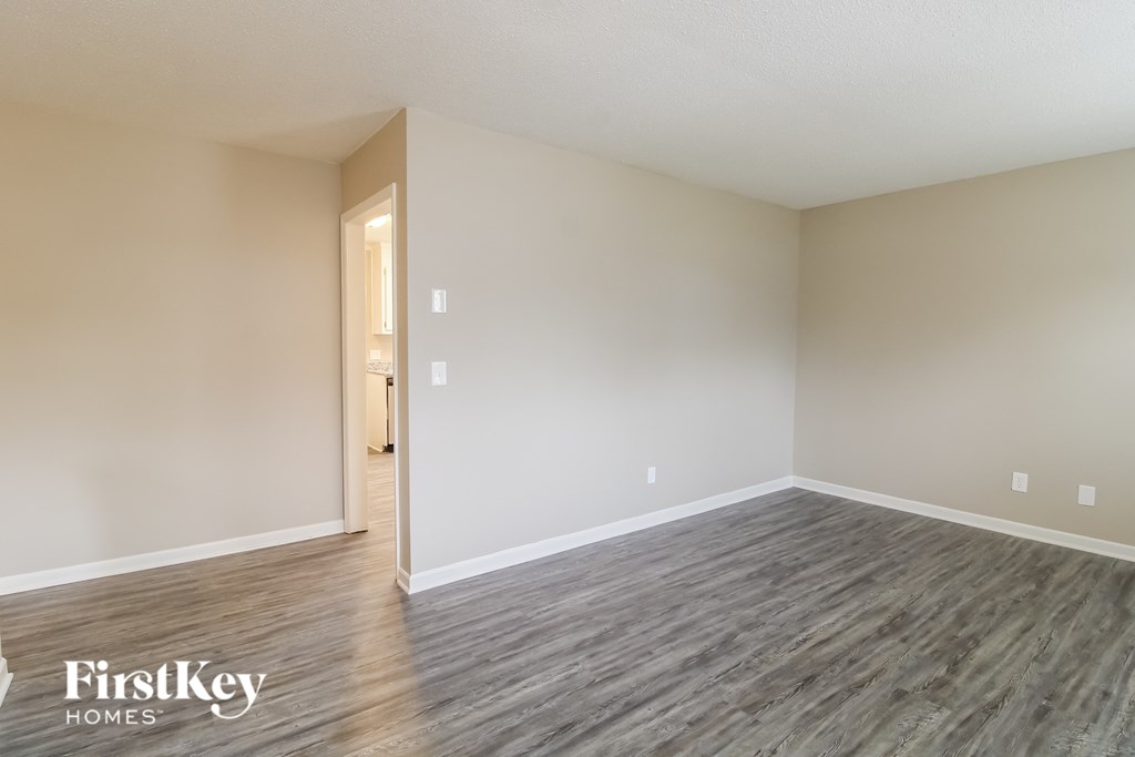 an empty living room with wood flooring and white walls