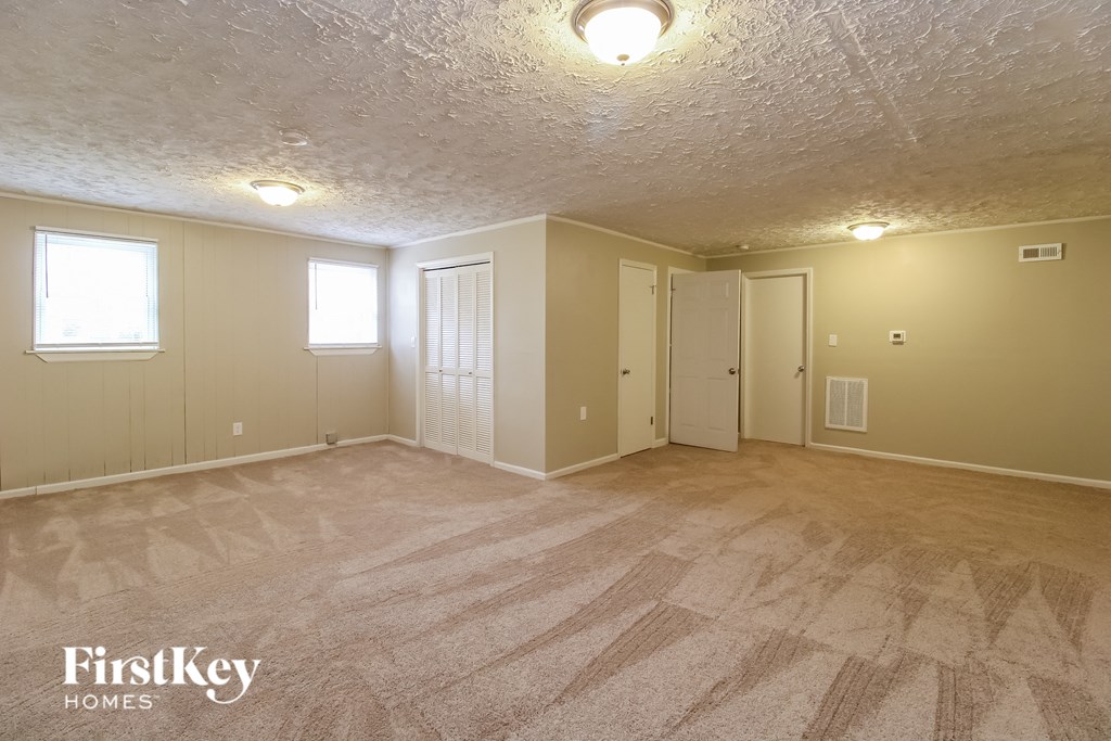 the living room of an empty house with carpet and a door to a closet