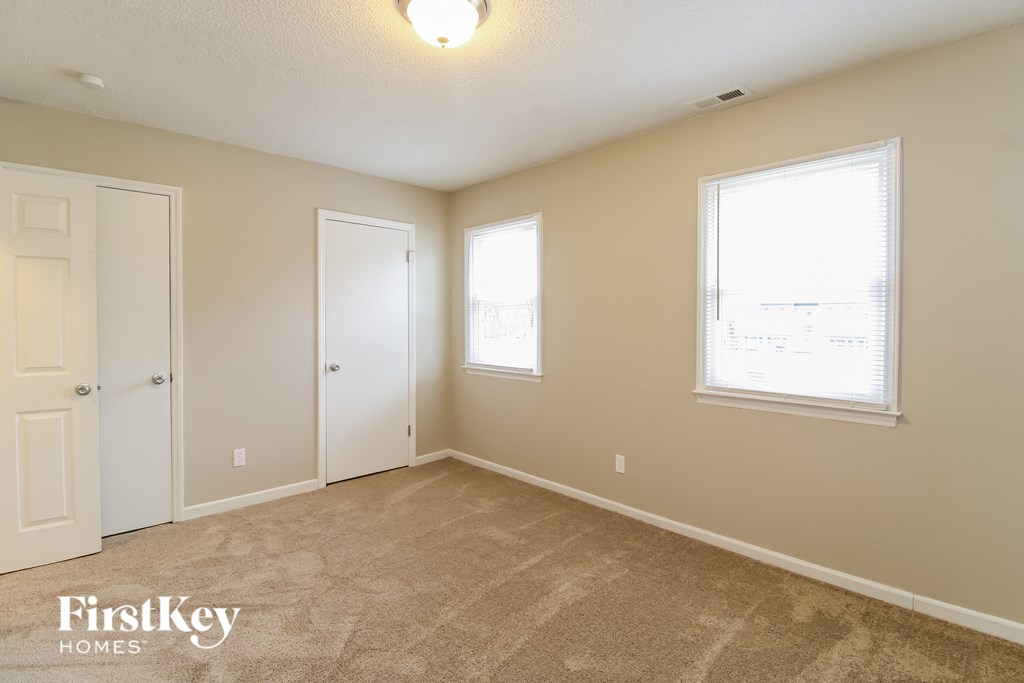 a bedroom with a carpeted floor and two windows