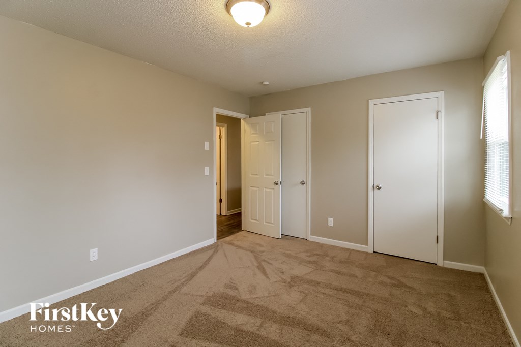 a living room with carpet and a door into a hallway