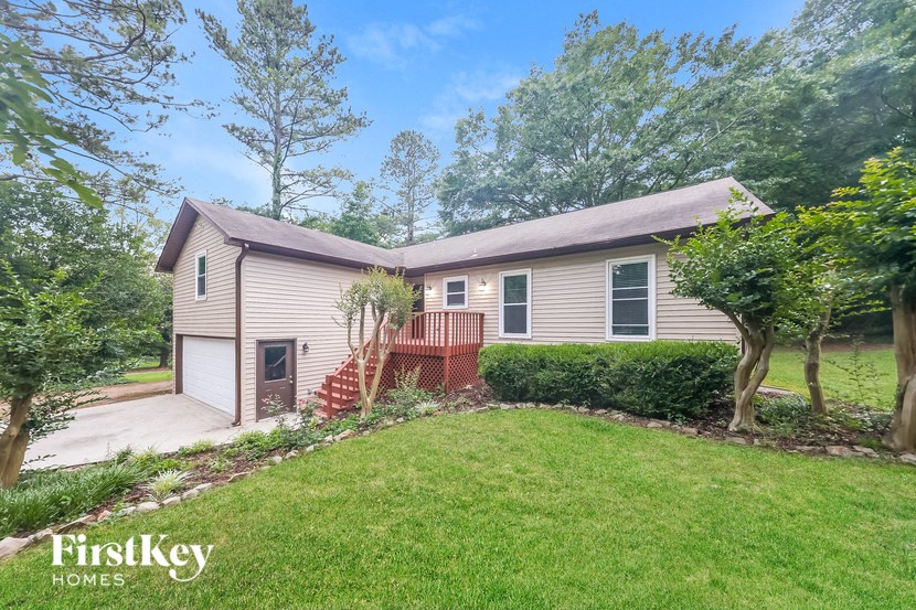 a small house with a yard and a deck and a driveway