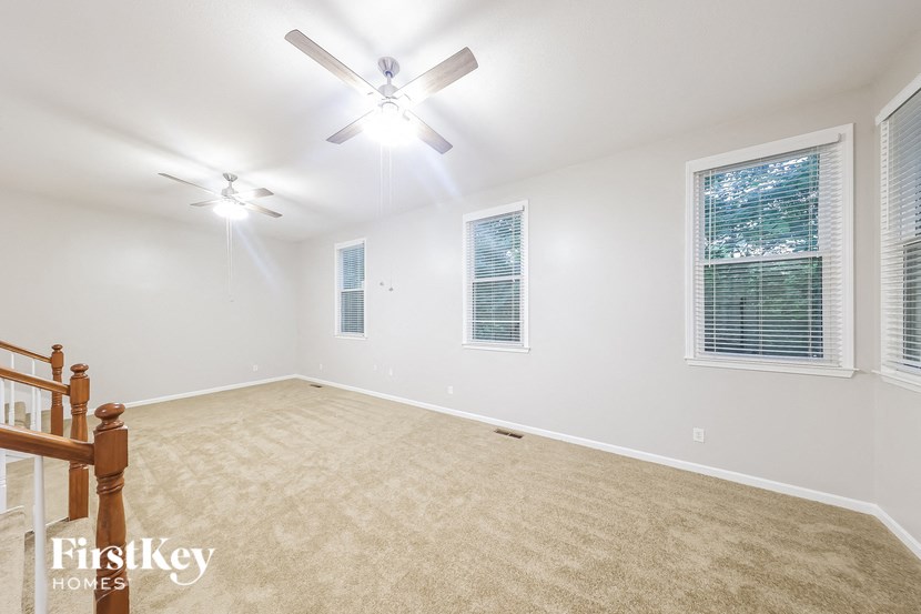 an empty living room with a ceiling fan and a window