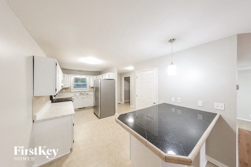 a large kitchen with white cabinets and a black counter top