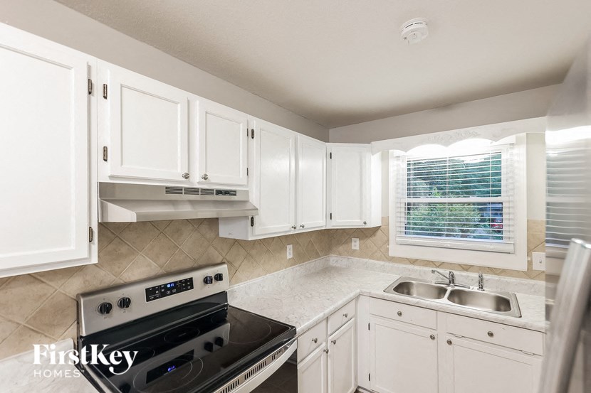 a kitchen with white cabinets and a stove and a sink
