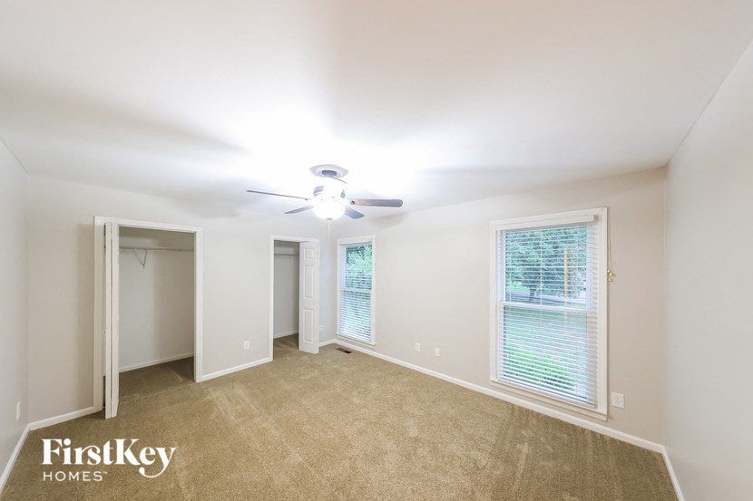 a bedroom with a ceiling fan and a large window