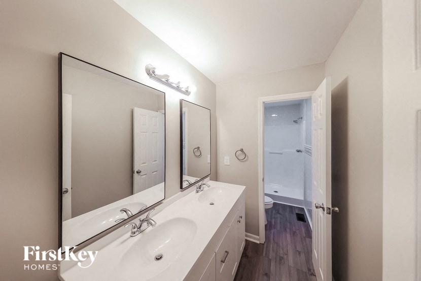 a white bathroom with two sinks and two mirrors