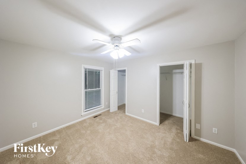 a bedroom with a ceiling fan and a door to a closet
