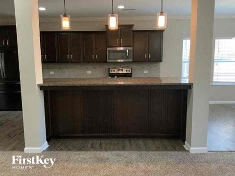 A kitchen with dark wood cabinets and a granite countertop.