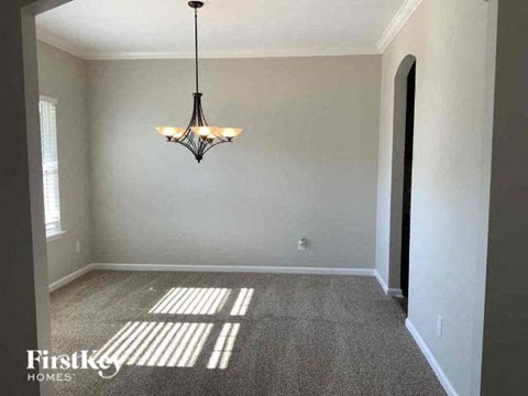 A room with a chandelier hanging from the ceiling and a carpet on the floor.