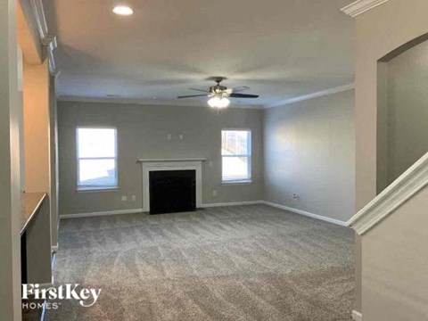 A spacious living room with a fireplace and a ceiling fan.