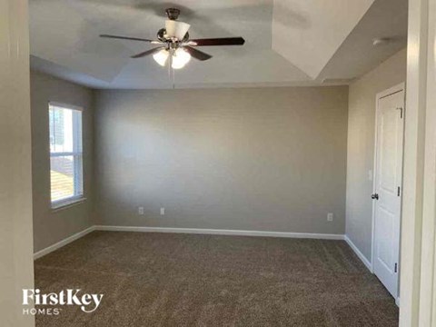 A room with a ceiling fan and a carpeted floor.