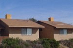 Two houses with brown roofs and tan walls.