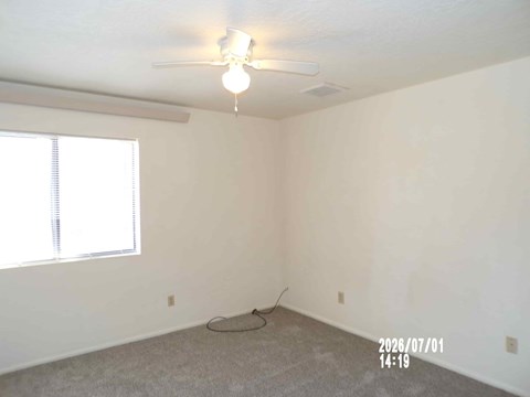A room with a ceiling fan and a window with blinds.