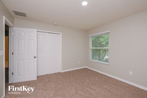 a bedroom with white doors and carpet and a window