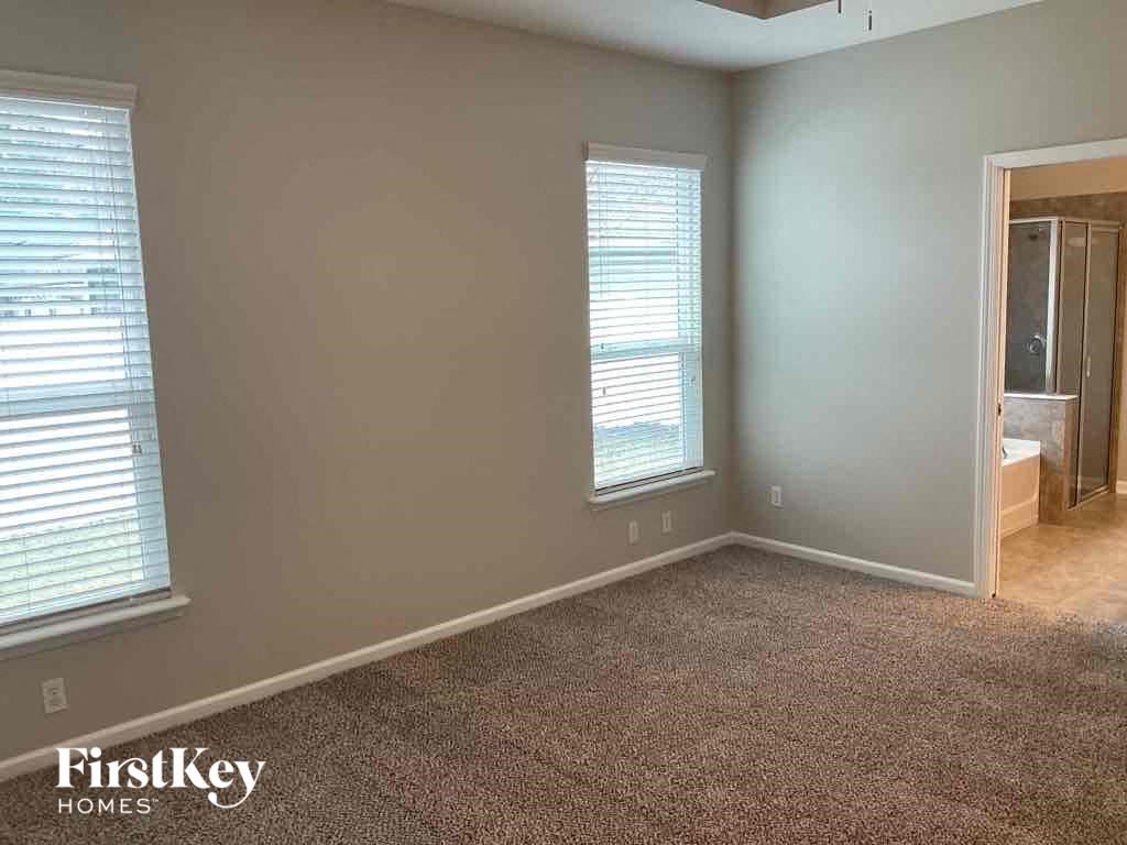 an empty room with a carpeted floor and two windows