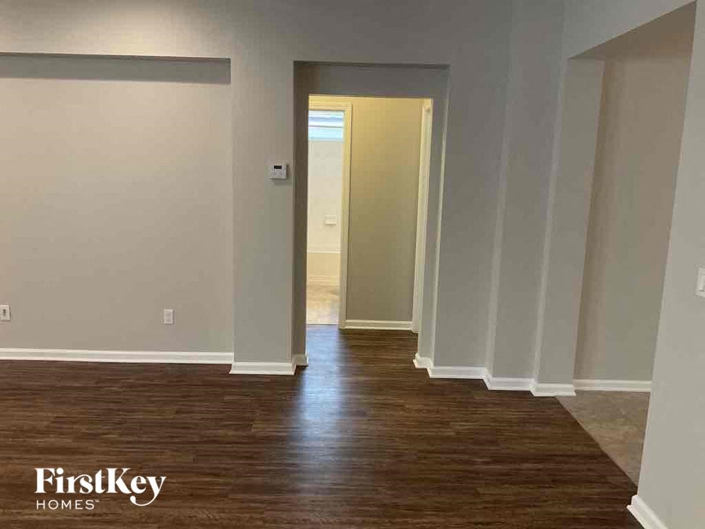 an empty room with a wood floor and a hallway to a closet