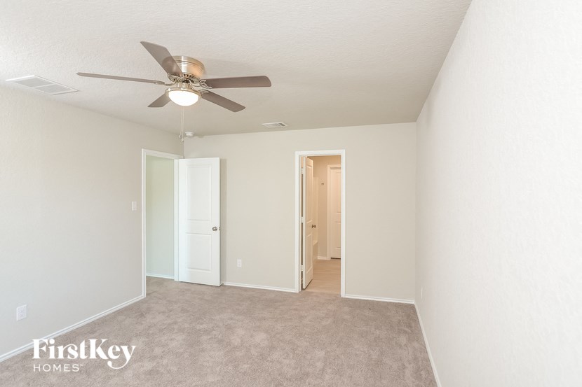 a bedroom with white walls and a ceiling fan