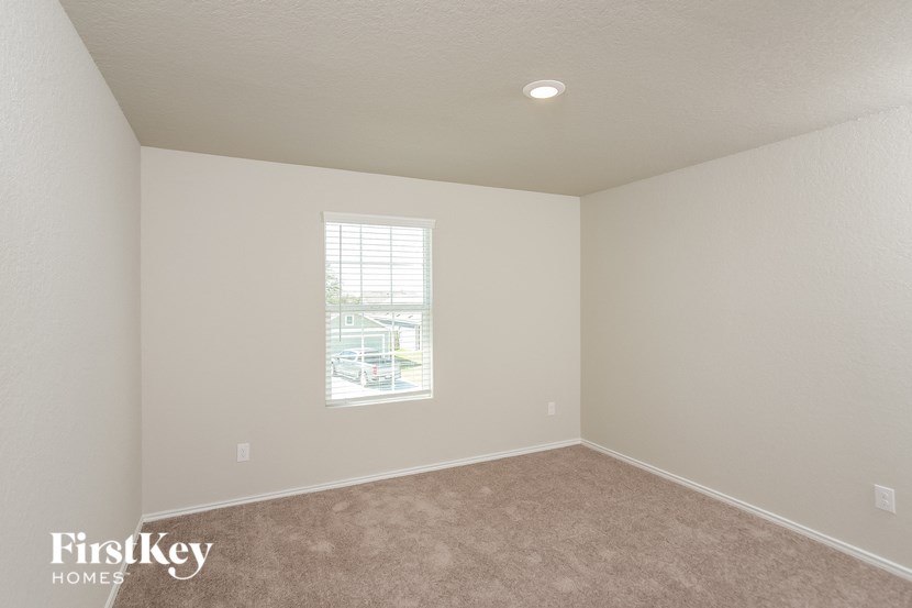 a bedroom with white walls and a window