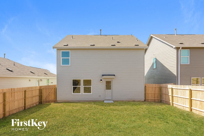 a backyard with a white house and a wooden fence