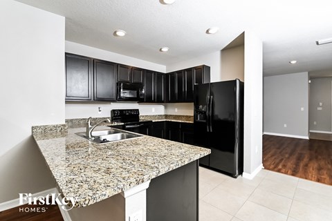 A kitchen with granite countertops and black appliances.