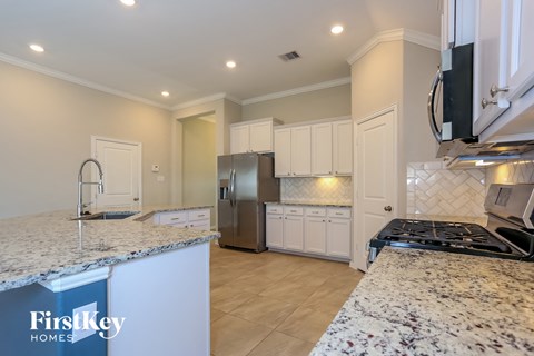 A kitchen with granite countertops and a stainless steel refrigerator.