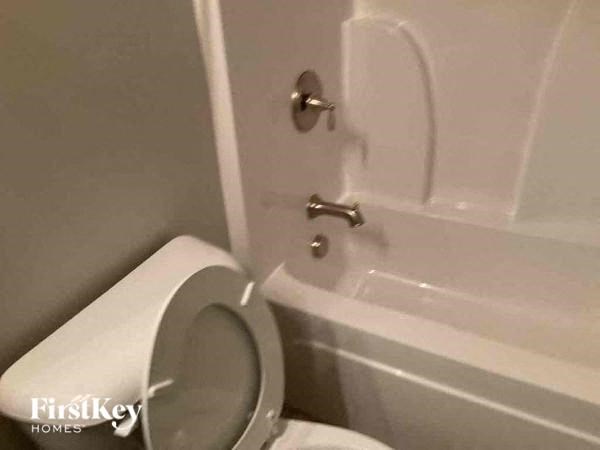 a bathroom with a white toilet and a tub