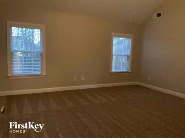 an empty room with two windows and a wooden floor