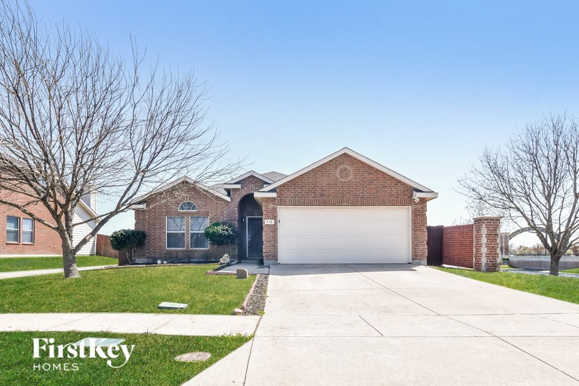 A brick house with a white garage door and a tree in front.