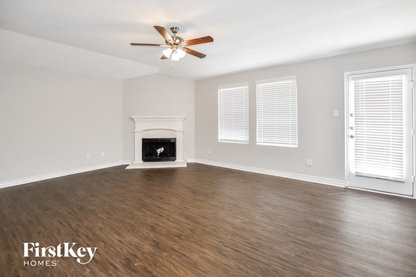 A spacious room with a fireplace and a ceiling fan.