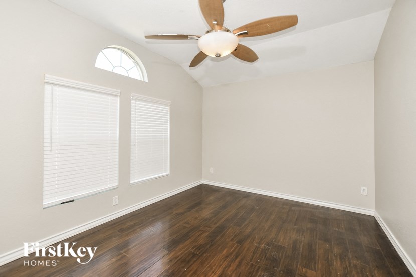 A room with a ceiling fan and wooden floors.