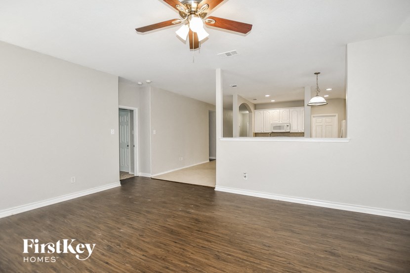 A spacious room with a ceiling fan and wooden flooring.