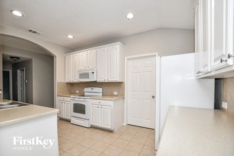 A kitchen with white cabinets and a FirstKey Homes sign.