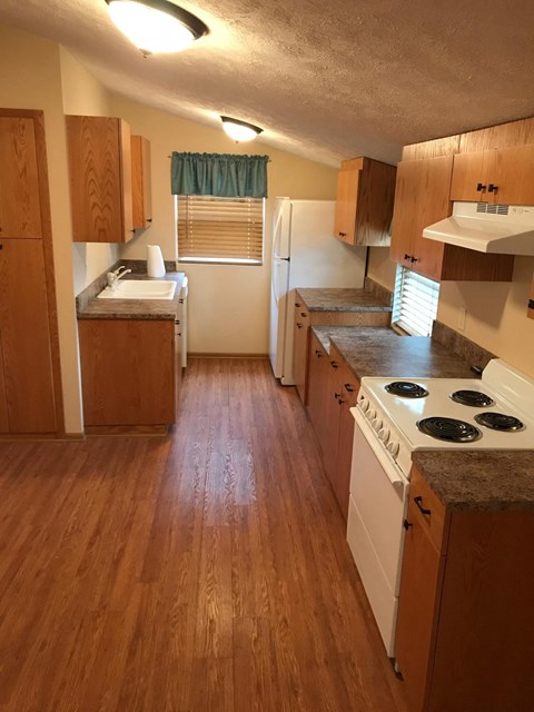 an empty kitchen with wood floors and white appliances