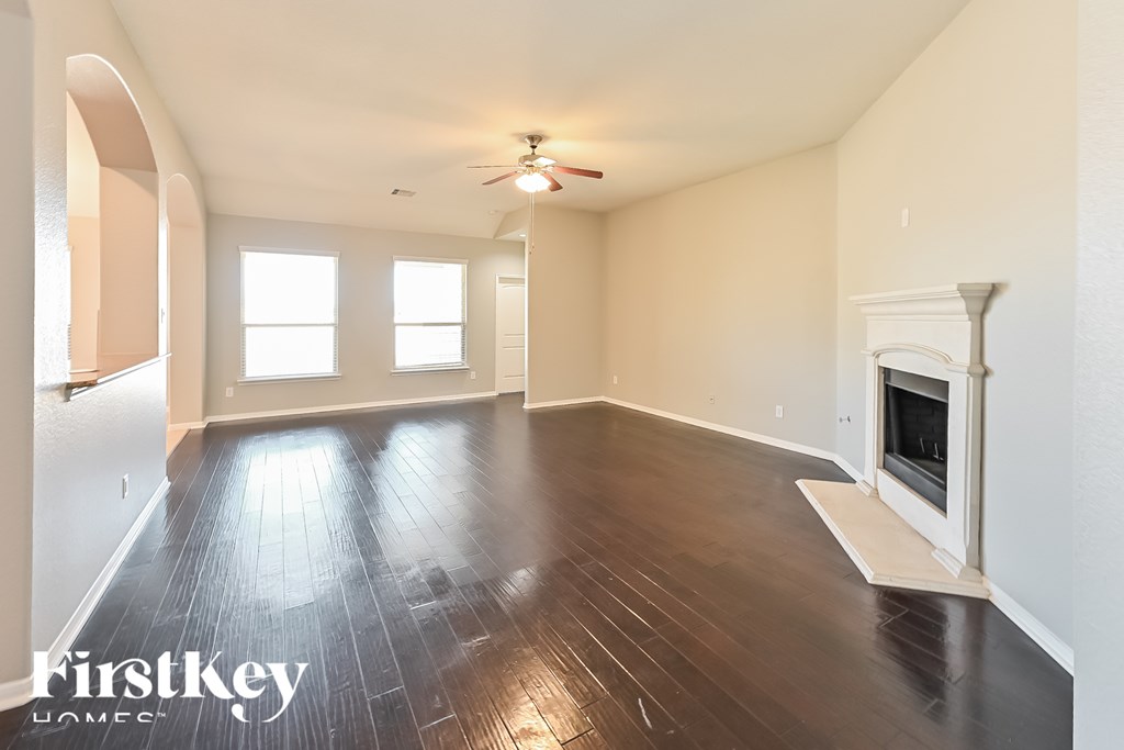 A spacious room with wooden floors and a fireplace.