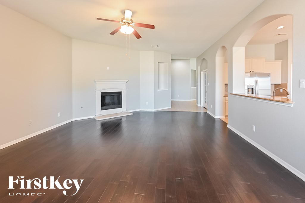 A spacious room with a fireplace and a ceiling fan.
