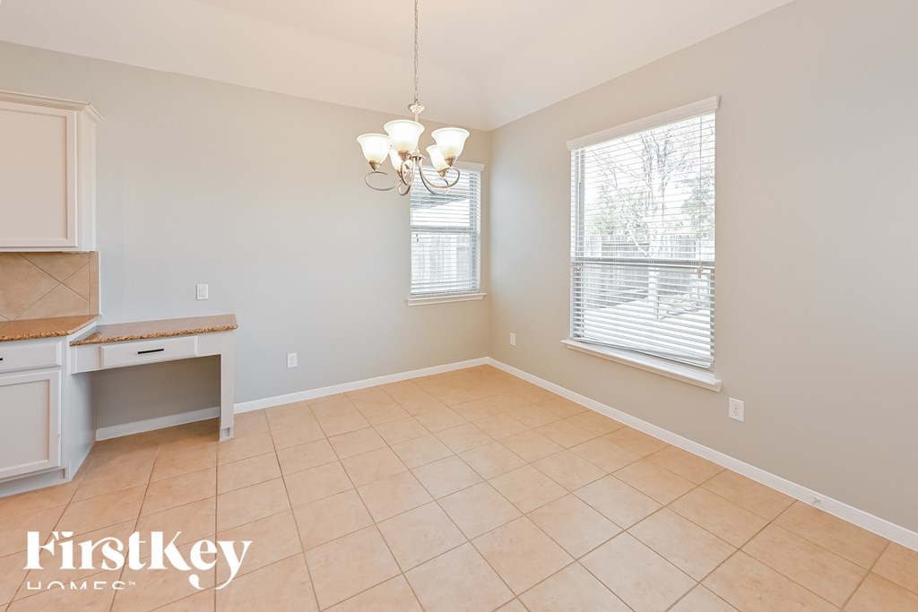 A room with a chandelier, a window with blinds, and a kitchen island.