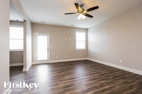 A spacious room with a ceiling fan and hardwood floors.