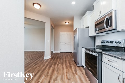 A kitchen with white cabinets and a wooden floor.