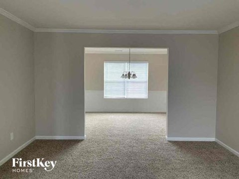 an empty living room with a window and a chandelier