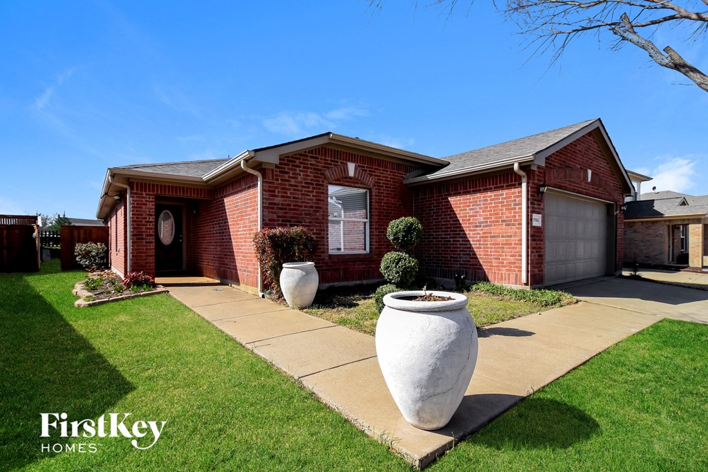 a red brick house with a sidewalk and vases in front