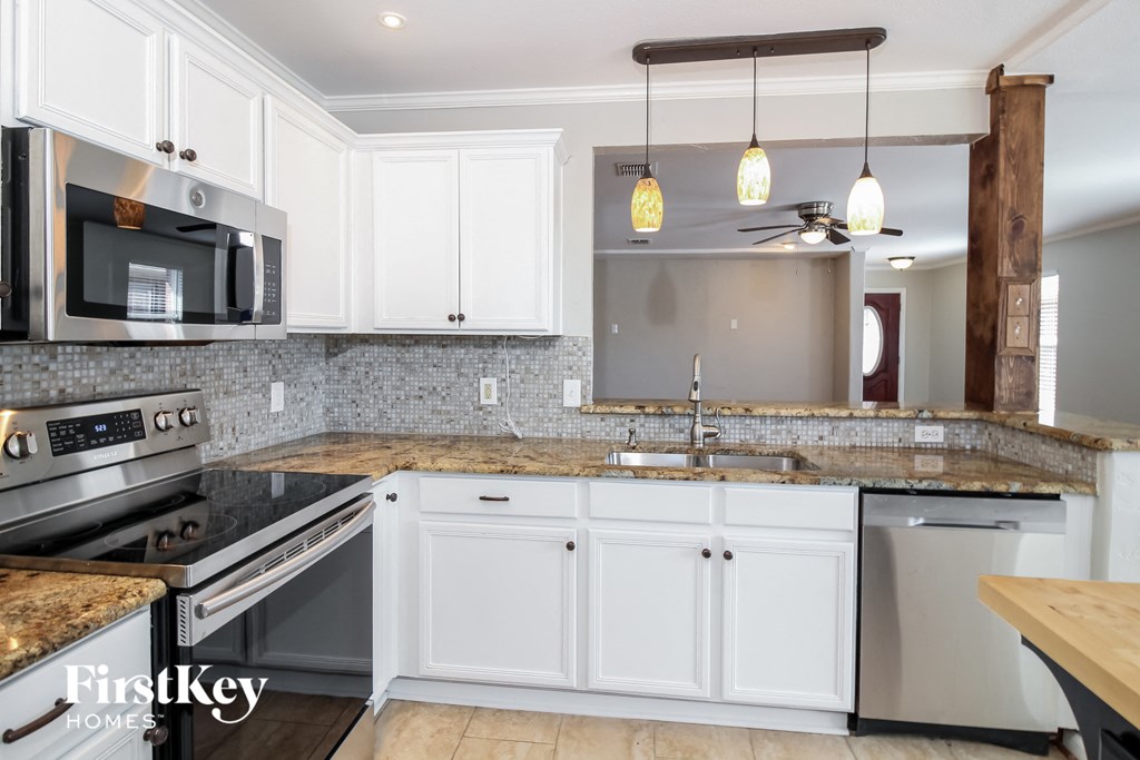 a white kitchen with granite counter tops and stainless steel appliances