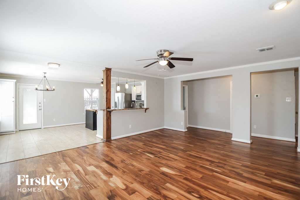 an empty living room with wood flooring and a ceiling fan