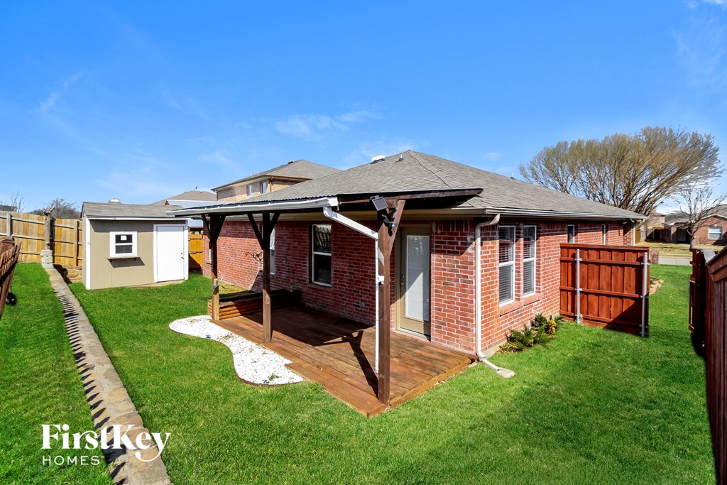 a backyard with a deck and a brick house